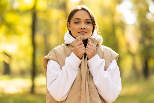 Young woman freezing in autumn park, cold autumn