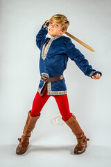 Child youth boy dressed as a cosplay prince pretending to fight a monster with his toy sword - obrazy, fototapety, plakaty