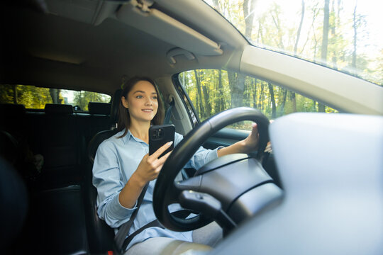Young woman sitting in car use mobile phone texting while driving dangerous