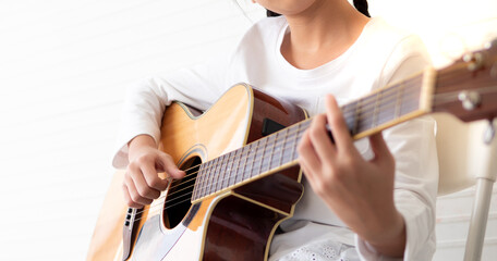 Talented female musician playing acoustic guitar on white background. Young asian guitarist put...