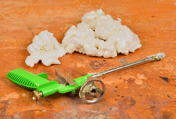 Spray gun for mounting foam on a wooden background close-up - obrazy, fototapety, plakaty