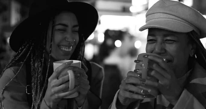 African Mother And Adult Daughter Drinking Hot Chocolate Together During Winter Time At Christmas Market