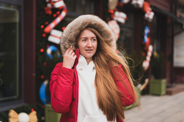 lovely woman in winter clothes walks down the street decorated with New Year's decor