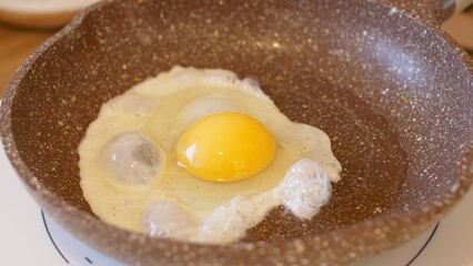 Close-up of frying pan with scrambled eggs into which another egg is broken to prepare fried eggs. Scrambled eggs breakfast to get strength for whole day. Routine preparation scrambled eggs breakfast.