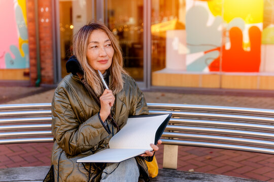 Portrait Of Happy Older Asian Woman  Writing On A Notebook  Outside It's Never Too Late To Earn A Degree Concept