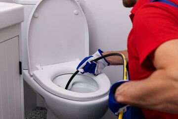 plumber unclogging blocked toilet with hydro jetting at home bathroom. sewer cleaning service - obrazy, fototapety, plakaty