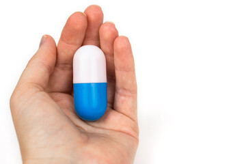 huge pill capsule in a female hand on a white background. medical drug or simple problem solution symbol