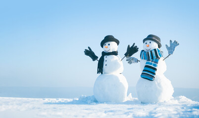 Snowman holding hands outdoors. Winter snowman in black hat, scarf and gloves. Christmas winter banner with snowman. Winter greeting card with with snowman. - obrazy, fototapety, plakaty