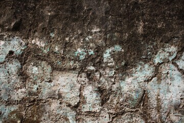 A weathered concrete wall with cracks and peeling paint, showing signs of age and decay.