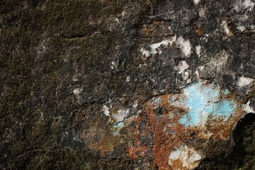 A weathered concrete wall with cracks and peeling paint, showing signs of age and decay.