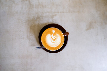 top view of cup of cappuccino with beautiful latte art on concrete background