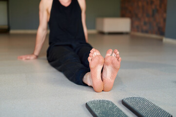 Fototapeta na wymiar Mans feet after standing on sadhu board (yoga board). Male sitting on the floor in yoga studio after practice indoors