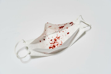 Medical mask with blood stain from coughing on white background. This can be because of Bronchitis,...