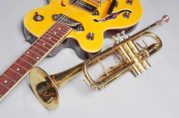 Obraz premium Yellow electric guitar and golden trumpet on a light background.