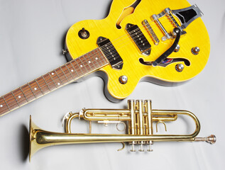 Obraz na płótnie Canvas Yellow electric guitar and golden trumpet on a light background.
