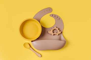 Brown silicone baby bib and and bowl. Serving baby. First baby accessories for dinner.  Top view, flat lay
