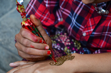 Nepali girl artist use henna ink write drawing paint mehndi henna tattoo as body art pattern on...