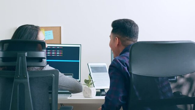 Young Asian man, developer programmer, software engineer, IT support,with colleague working on computer to check coding in bugging system and running program successful.