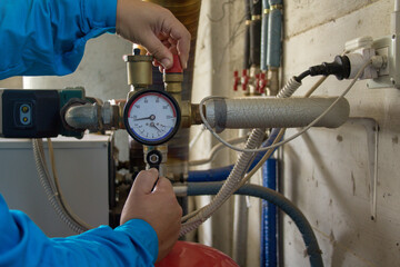 Image of the hands of a plumber who opens a hot water tap of a boiler. First ignition of a boiler...