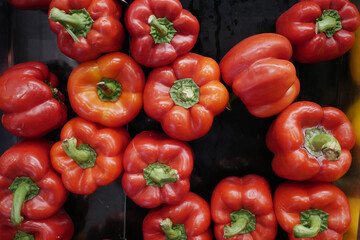 overhead view of many red capsicum on black 