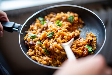 cooking tasty rice, meat and vegetable in pan on kitchen