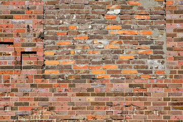 Background, brick wall made old German red burnt brick with traces bullets and shrapnel after World War II.