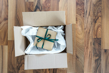 Ein Geschenk mit grüner Schleife in einem Versand Karton. 