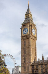 The clock tower of Westminster palace, commonly known under the name of its bell - Big Ben - located in London, UK. The London Eye, another well known landmark is visible in the background.