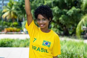 Cheering young woman from Brazil with yellow football jersey