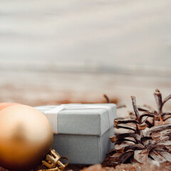 Christmas toys - golden balls and a gift box on the beach, blurred sea in the background. New Year or Christmas card, invitation with copy space for text