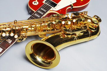 Electric guitar and golden saxophone on a light background.