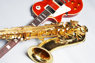 Electric guitar and golden saxophone on a light background.