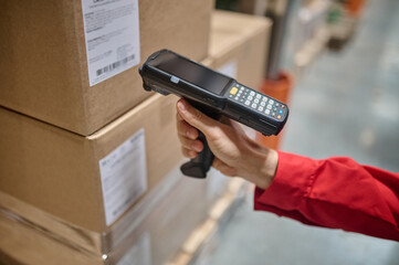 Warehouse employee scanning packaging information using a scanner - obrazy, fototapety, plakaty
