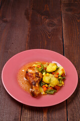 Baked chicken drumstick with vegetables potatoes green beans in sauce and spices on a wooden table.copy space