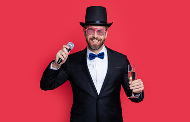 Naklejka premium magician man cheering with microphone. man magician wear tuxedo in studio.