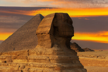 Obraz na płótnie Canvas Sculpture of the Sphinx against the background of the Priamis of Cheops on the Giza plateau in Egypt against the background of the picturesque sky