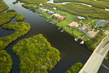 Aerial view of residential suburbs with private homes located near wildlife wetlands with green vegetation on sea shore. Living close to nature concept