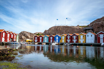 Beautifull fishermans village in swedish town called Smögen. Colorfull fishermans hut with boats and coastline. Scandinavian architecture. Red and green facade made of wood.