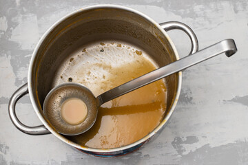 a cooking pot and kitchen spoon after use for soup