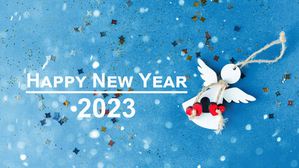 Happy New Year 2023. New Year's card with angel on a blue background. Blurred lights in the...