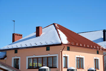 Closeup of house roof top covered with snow in cold winter. Tiled covering of building in wintertime weather