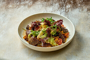 Salad with liver and greens in a plate. Close-up, selective focus.