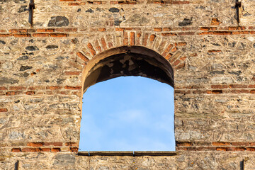 oval window in brick building opening to sky, aged round window