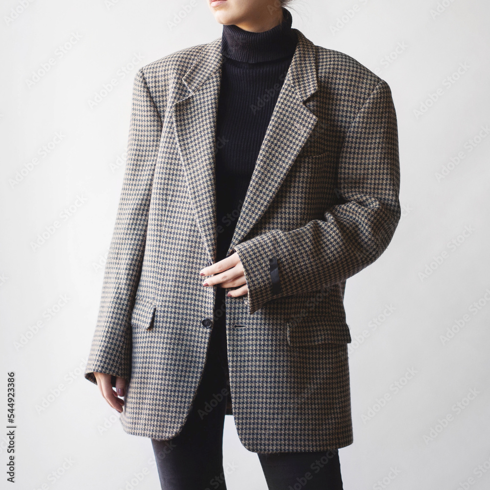 Wall mural Woman wearing black turtleneck, oversized check blazer and black jeans isolated on white background