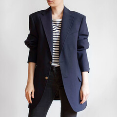 Woman wearing oversized navy blazer, striped t-shirt and black jeans isolated on white background