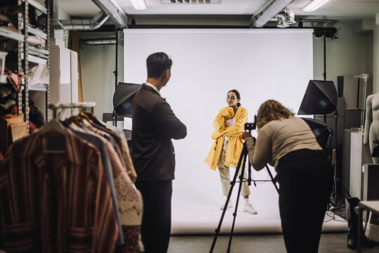 Female fashion model posing against backdrop during photo shoot at studio