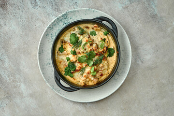 Baked draniki in cream sauce with bacon on a plate on a textured background. Close-up, selective focus
