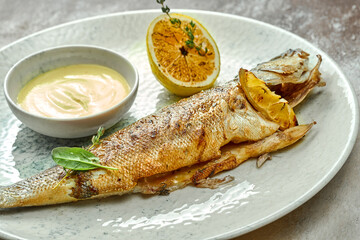 Whole fried seabass with sauce in a plate. Close-up, selective focus