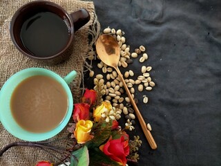 Obraz na płótnie Canvas cup of coffee, spoon and a rose on black background