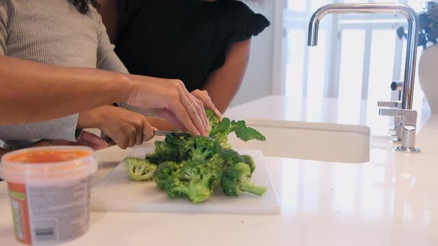 Mother and daughters preparing broccoli in kitchen